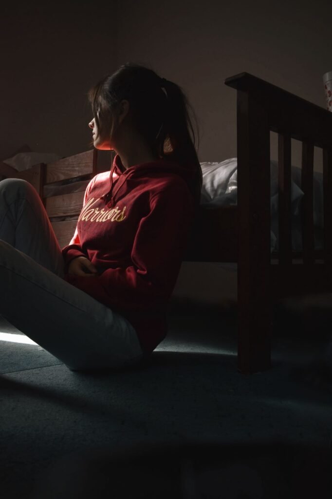 A girl who sit on the floor with support of bed